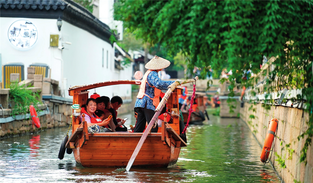 游客乘船在苏州平江历史文化街区休闲游玩（2023年7月3日摄）。李博摄/本刊